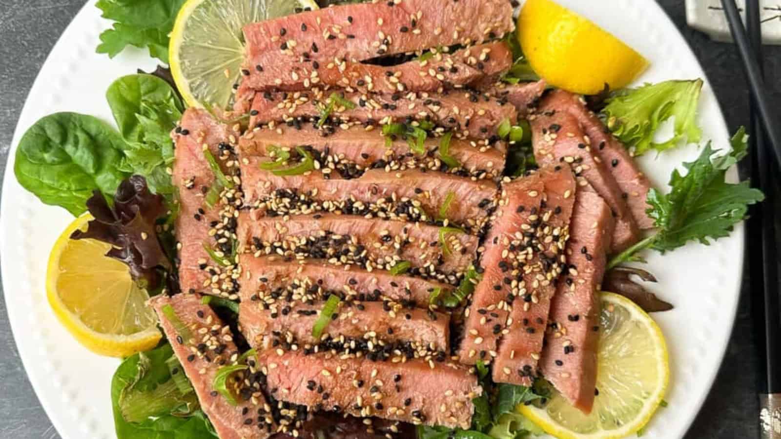 Perfectly air-fried ahi tuna steaks with greens and lemon slices on a plate.