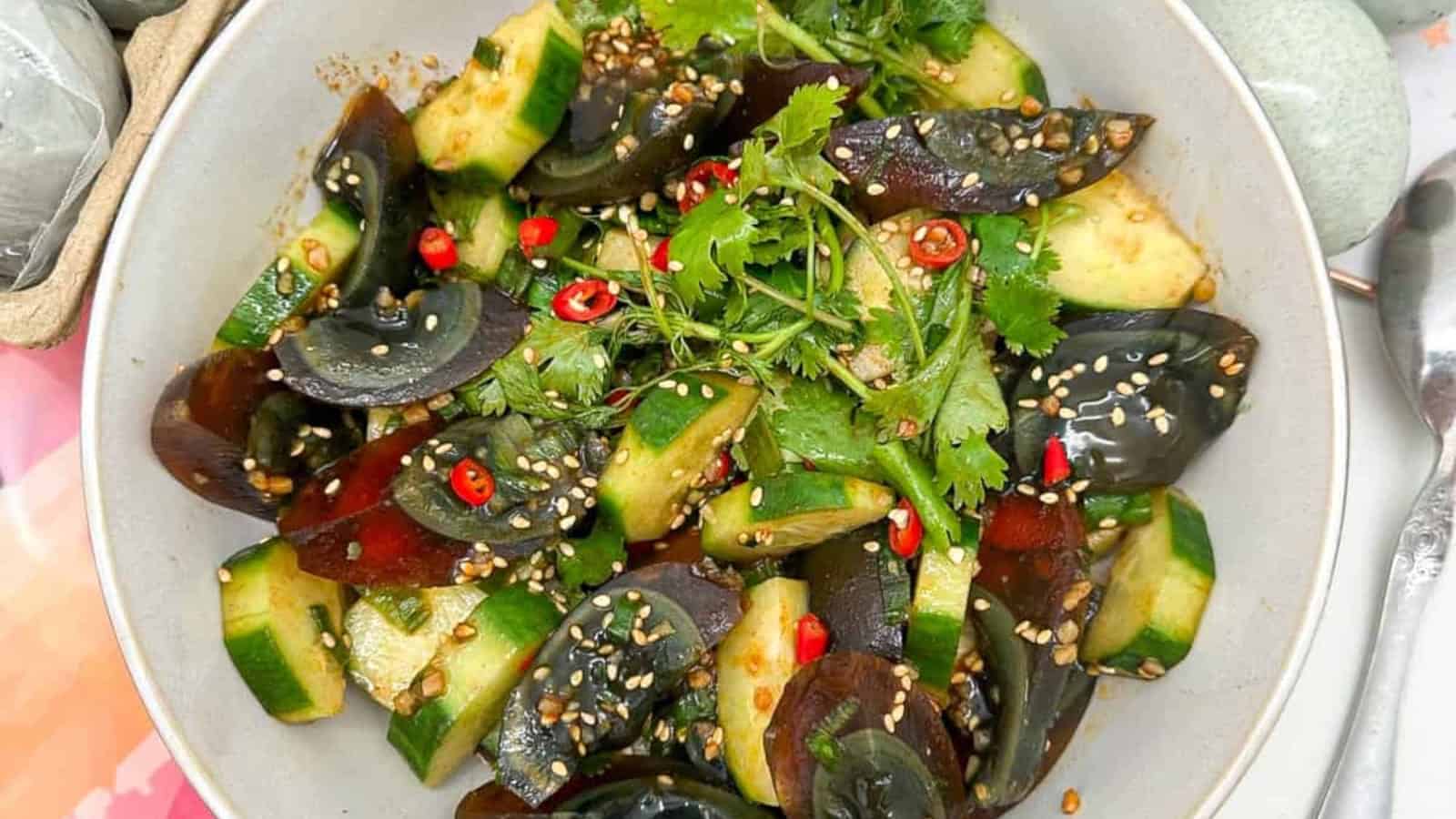 Unique and flavorful century egg salad paired with crisp cucumber in a white bowl.