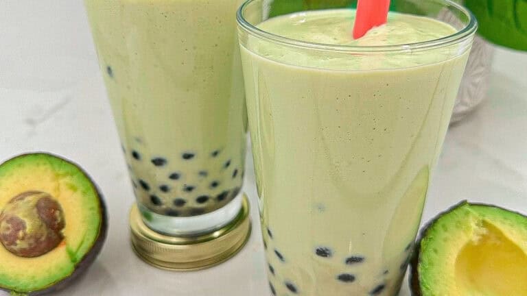 Creamy avocado smoothie with chewy boba pearls in glasses with a red color straw.