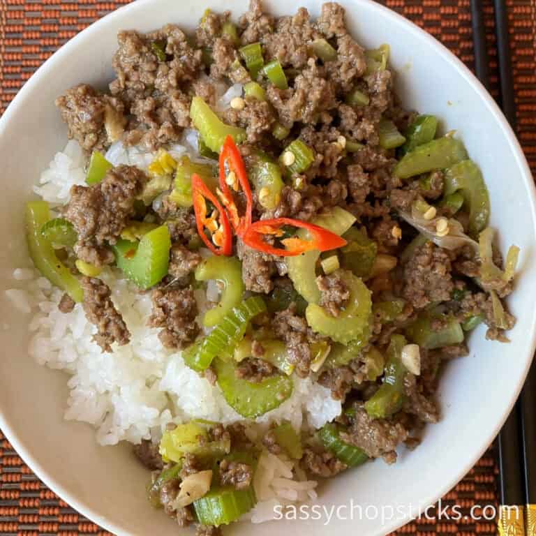 Ground beef stir fry with celery over rice in a while bowl.