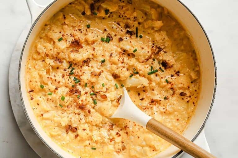 Cauliflower cheddar cheese bacon soup in a pot with a spoon.