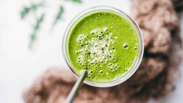Green arugala smoothie in a glass.