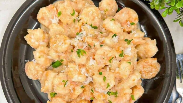Juicy shrimp cooked in creamy coconut sauce, just like buffet-style on a black plate.
