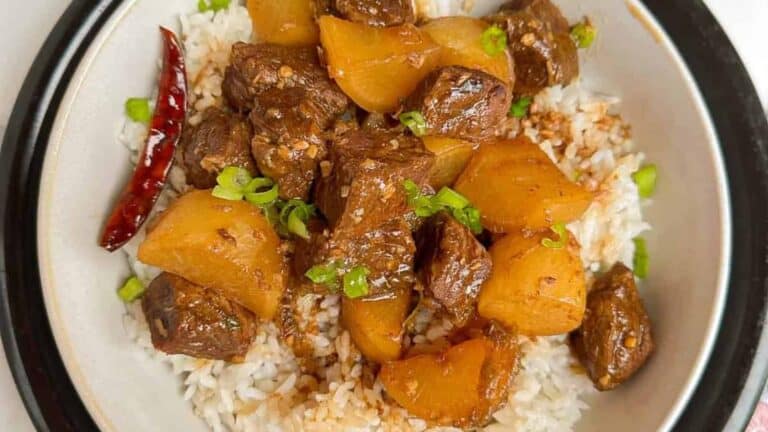 Tender and hearty Chinese braised beef stew with daikon radish in a bowl with fluffy rice.