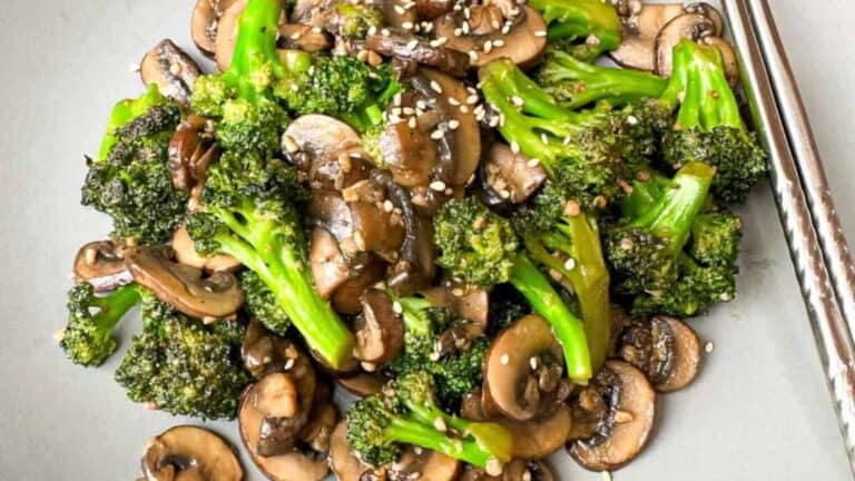 Healthy and flavorful stir-fry with fresh broccoli and mushrooms on a plate with a pair of silver color chopsticks.