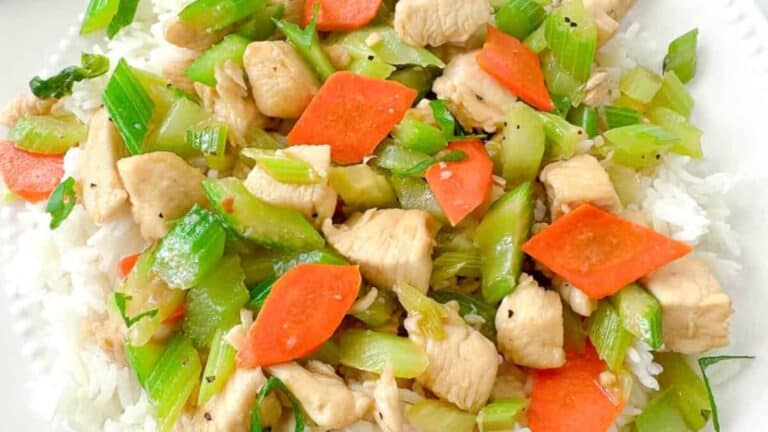A dish of stir-fried chicken and celery pieces served on a white plate.
