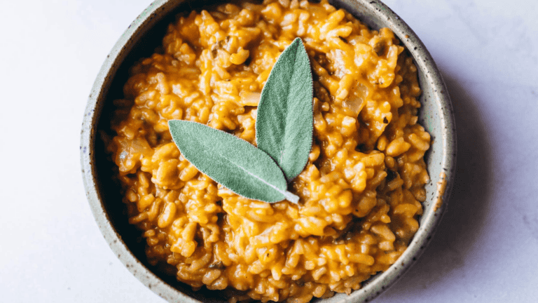 Creamy pumpkin risotto topped with fresh sage leaves in a rustic bowl.