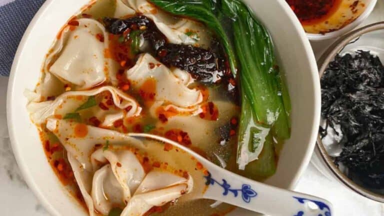 Warm and comforting soup with delicate wontons in a clear, savory broth in a white bowl.