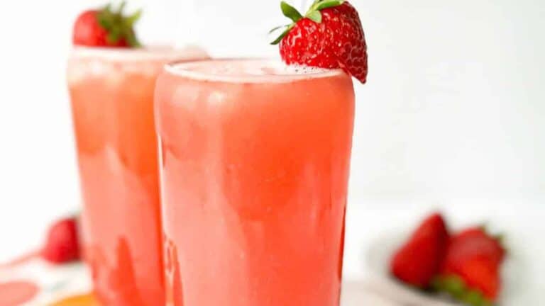 Two glasses of strawberry green tea drink, each topped with a strawberry.