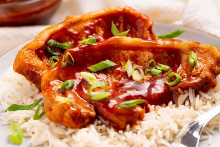 Slow cooker pork chops with rice and sauce on a plate.