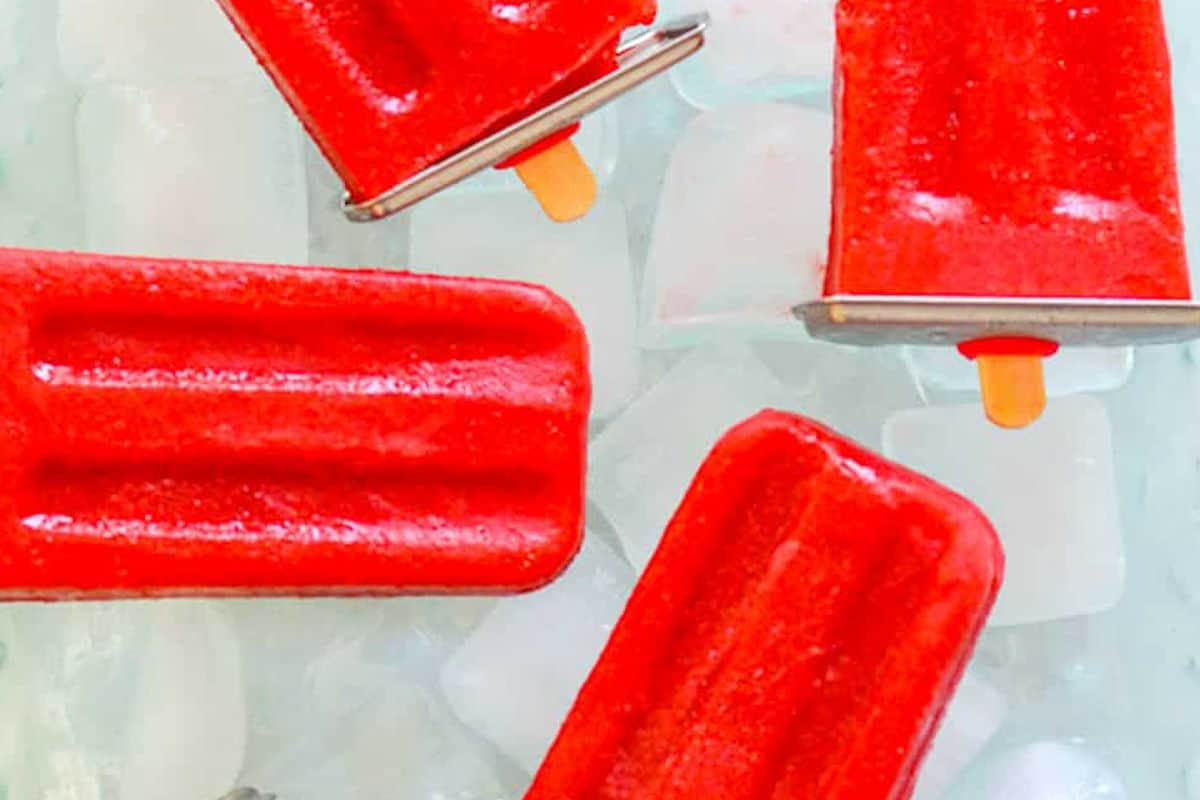Strawberry popsicles on top of ice.