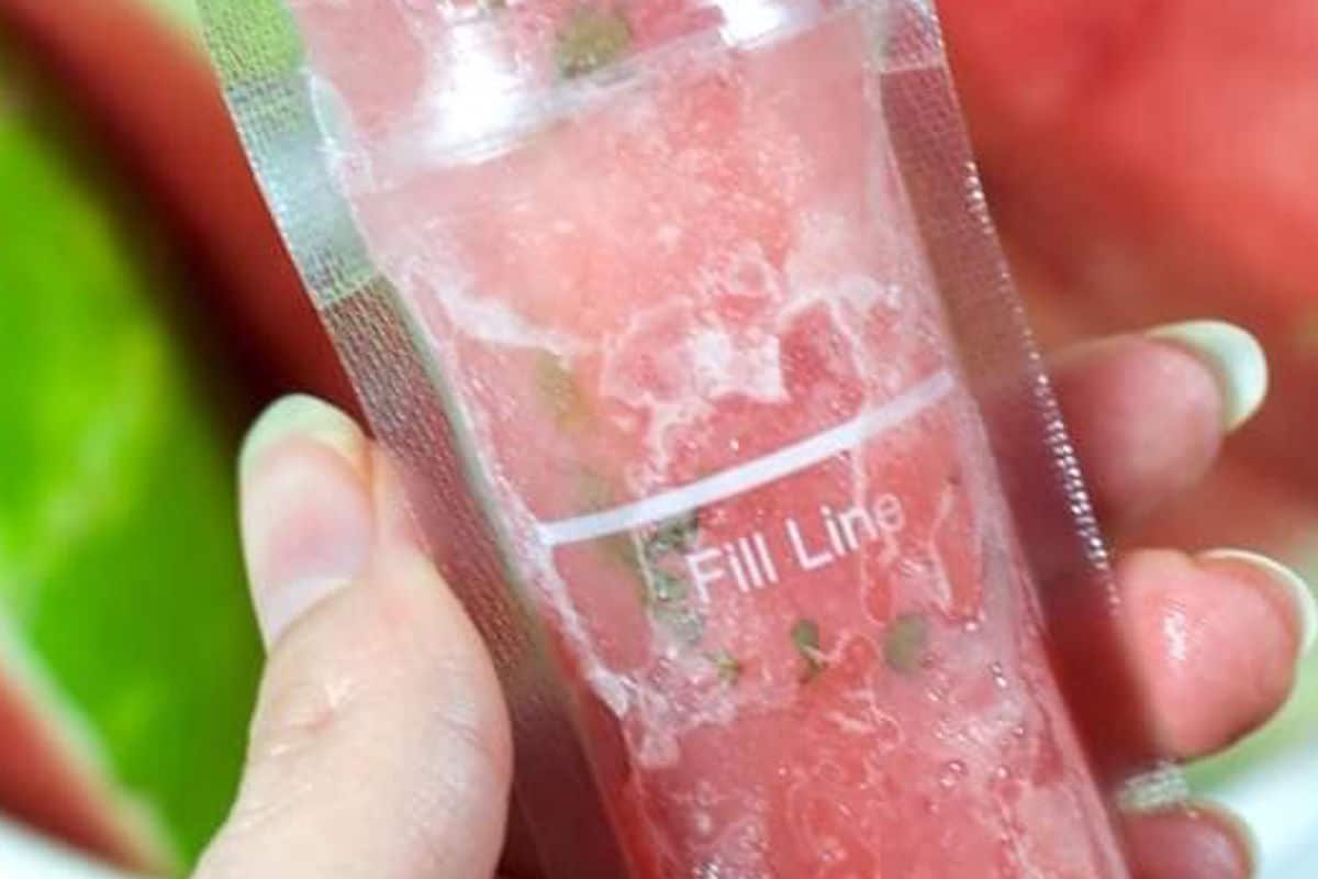 A hand holding a watermelon mojito popsicles.