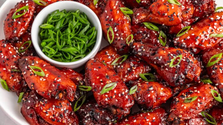 Delicious Korean chicken wings garnished with sesame seeds and green onions on a plate.