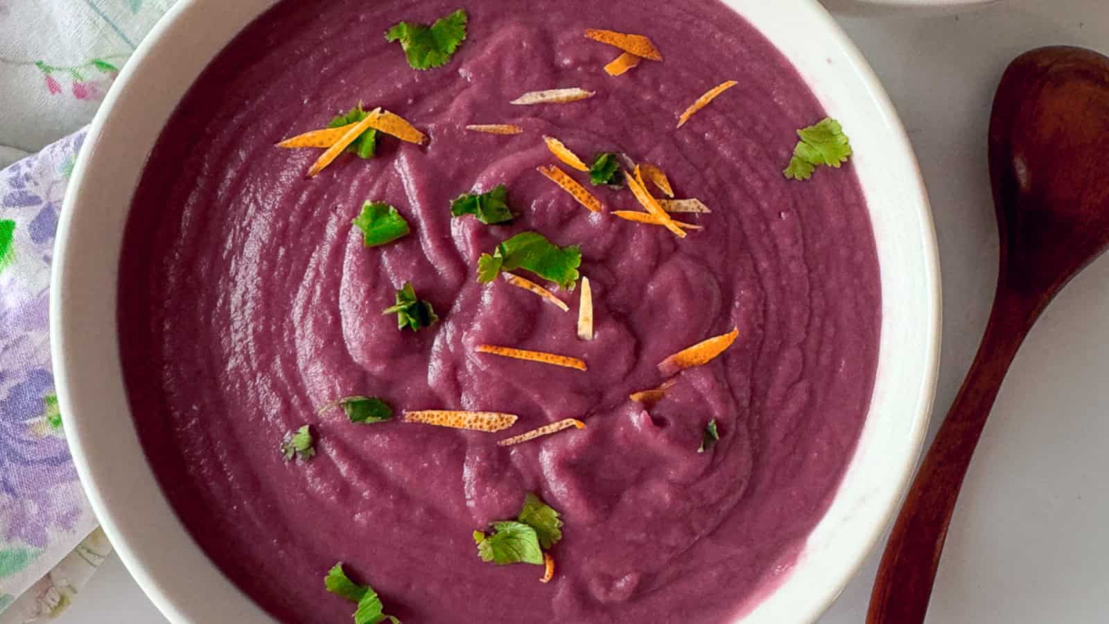 A bowl of purple yam soup with garnish.