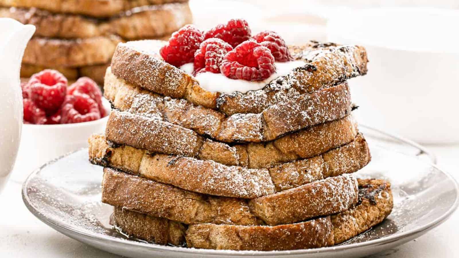 A golden slice of French toast topped with fresh berries and a drizzle of maple syrup, served on a white plate.