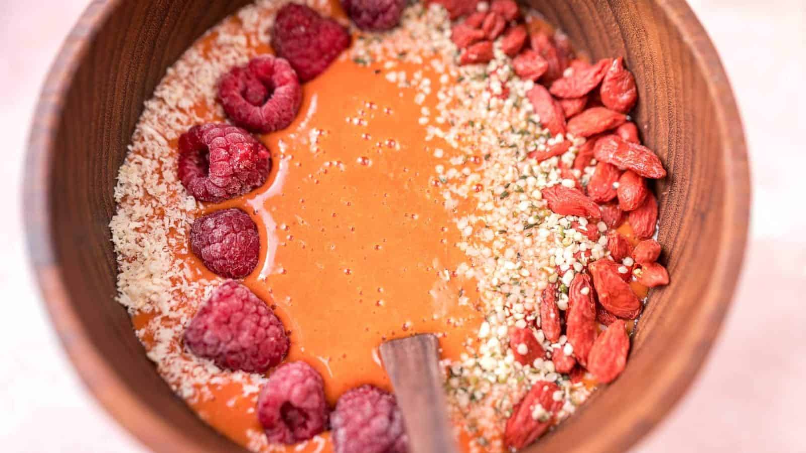 Vibrant goji berry smoothie bowl topped with fresh fruit and seeds, served in a bowl.