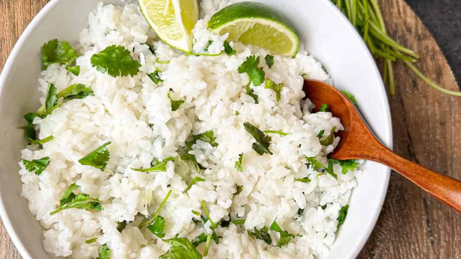 Fluffy coconut lime rice in a bowl with a brown wooden spoon.