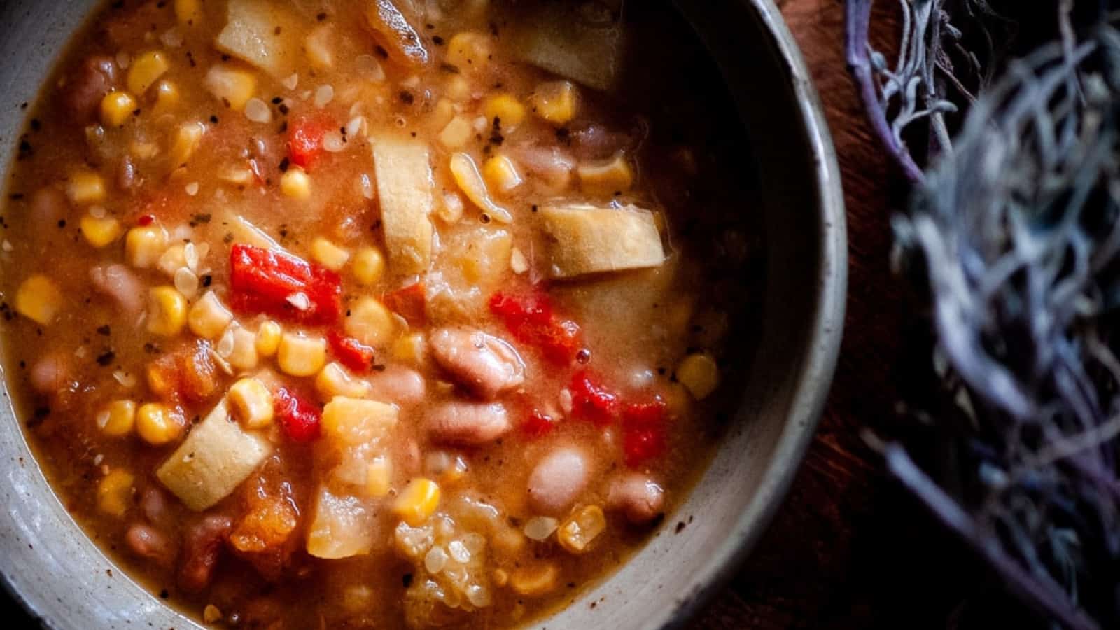 A bowl of Instant Pot Three Sisters Soup, filled with corn, beans, and squash in a flavorful broth, garnished with fresh herbs.