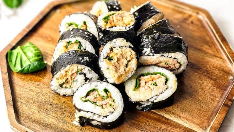 Spicy tuna kimbap on a wood cutting board.