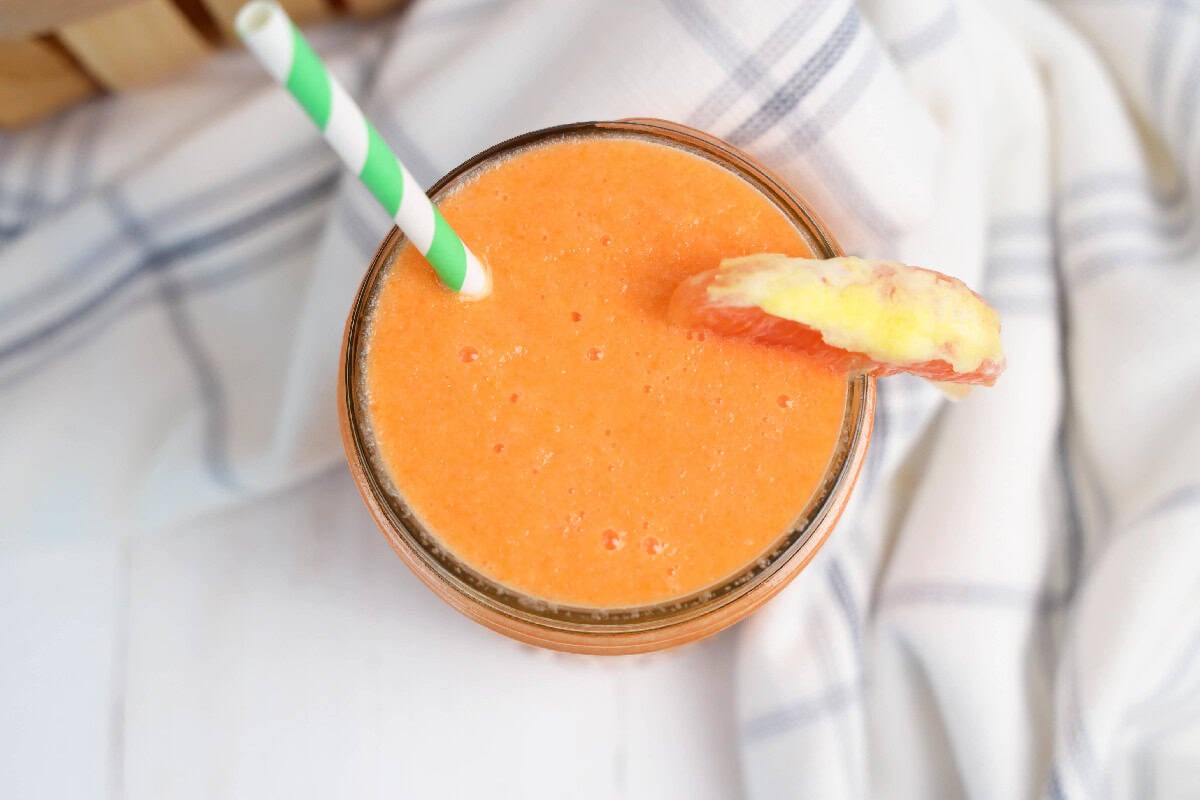 A smoothie with orange slices and a straw.
