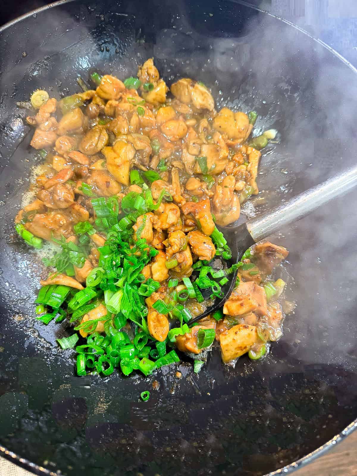 Cooking chinese scallion chicken in a wok.