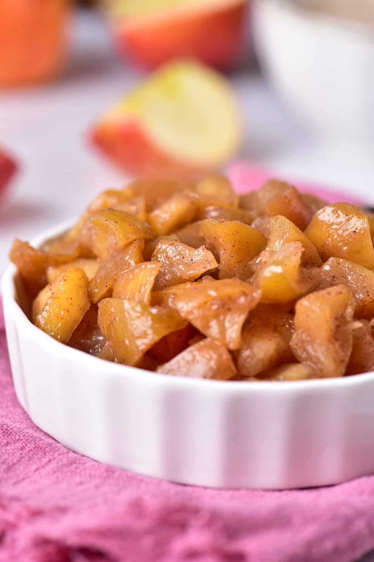 Cooked red apples in a bowl, resting on a cozy pink towel.