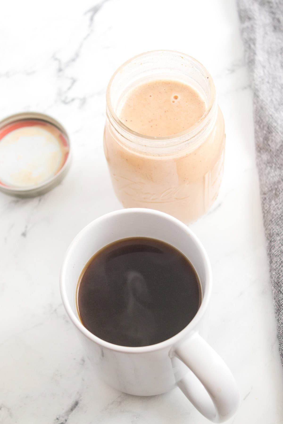 A cup filled with homemade pumpkin-flavored creamer and a black coffee.
