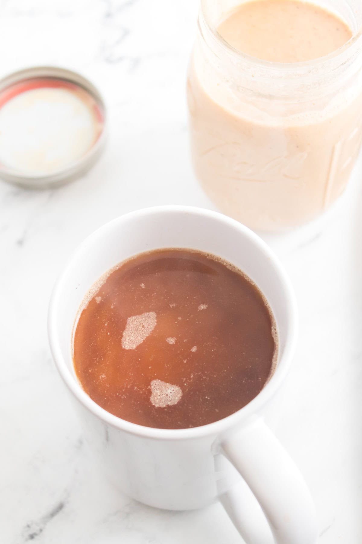 A cup filled with homemade pumpkin-flavored creamer and a black coffee.