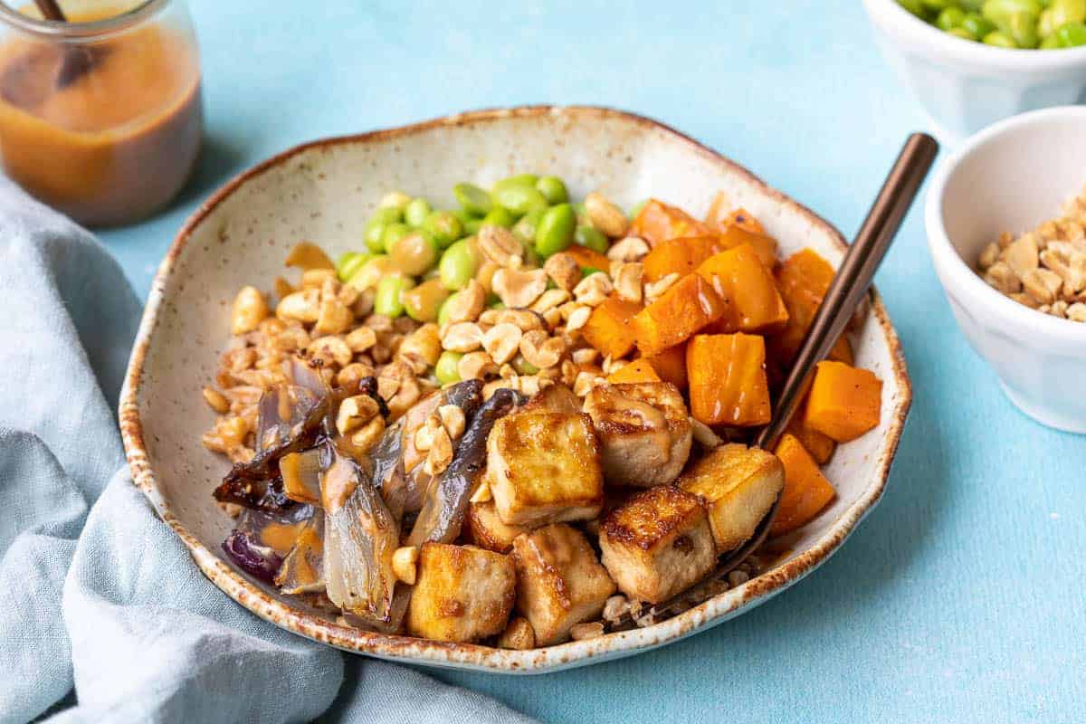 Tofu Buddha bowl with rice, roasted veggies, and sesame seeds.