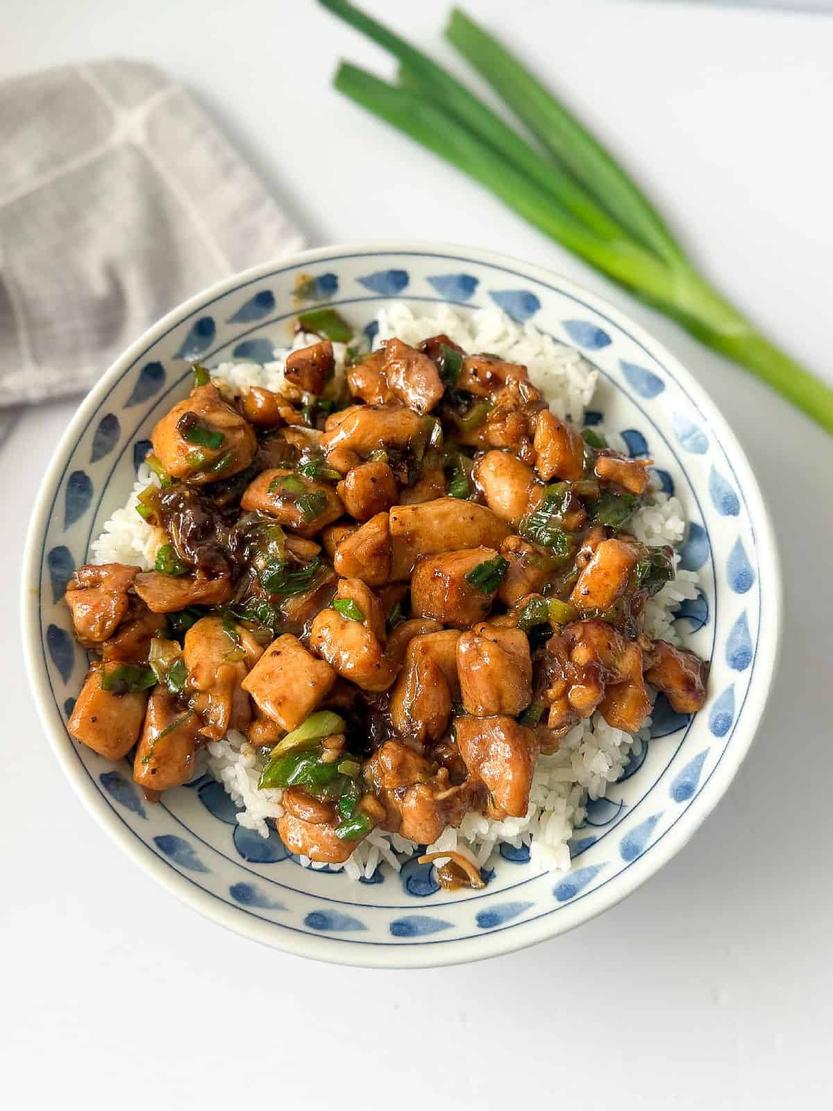 Chinese scallion chicken cooked with scallions and sauce, presented in a colorful bowl.