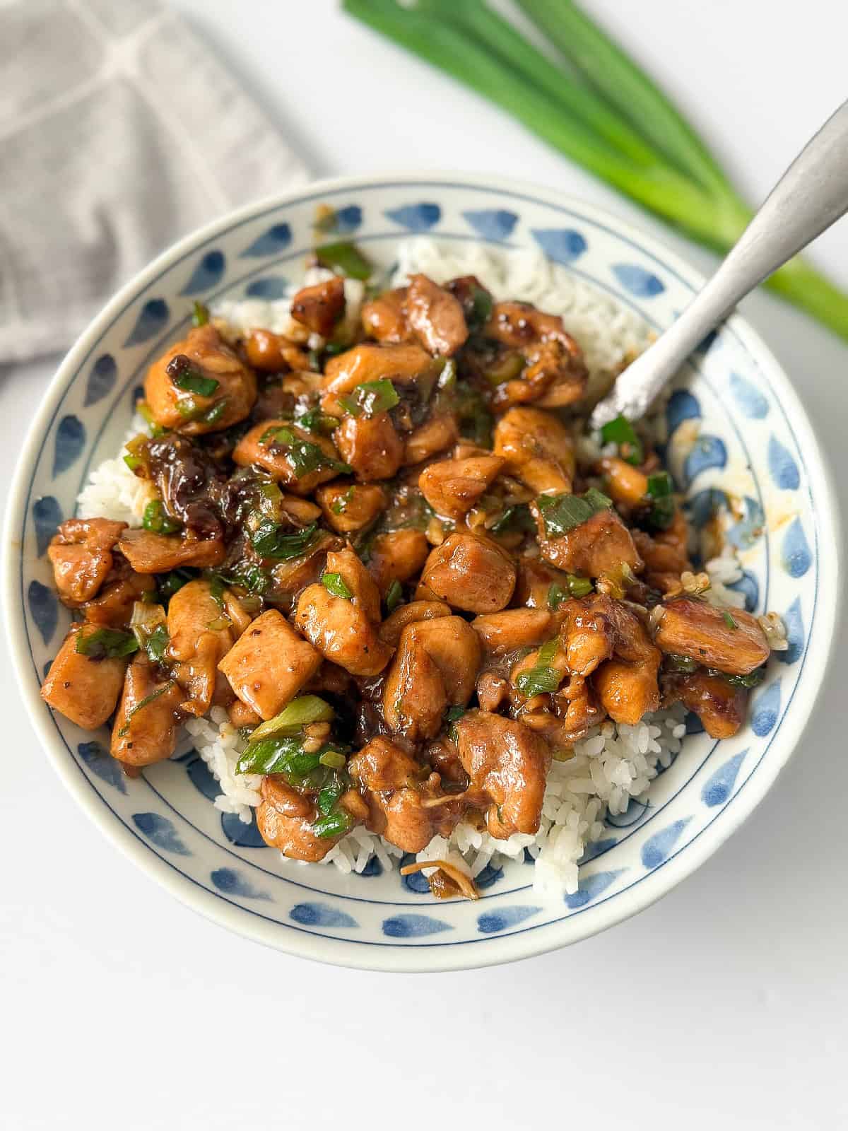Chinese scallion chicken cooked with scallions and sauce, presented in a bowl.