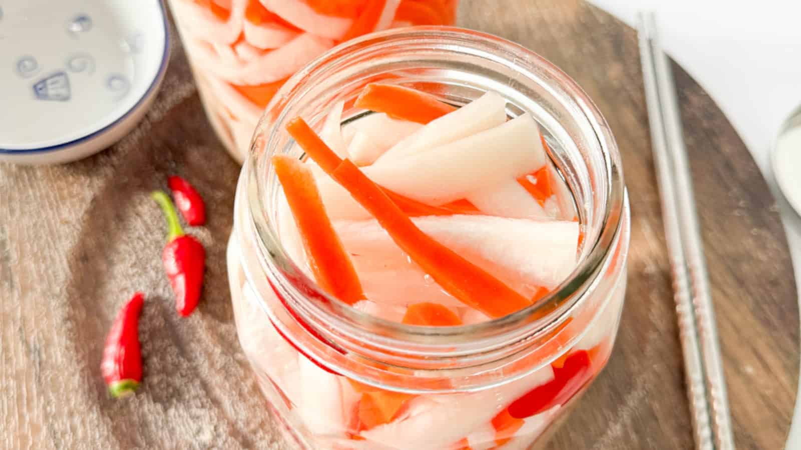 Pickled daikon and carrots in a glass jar.