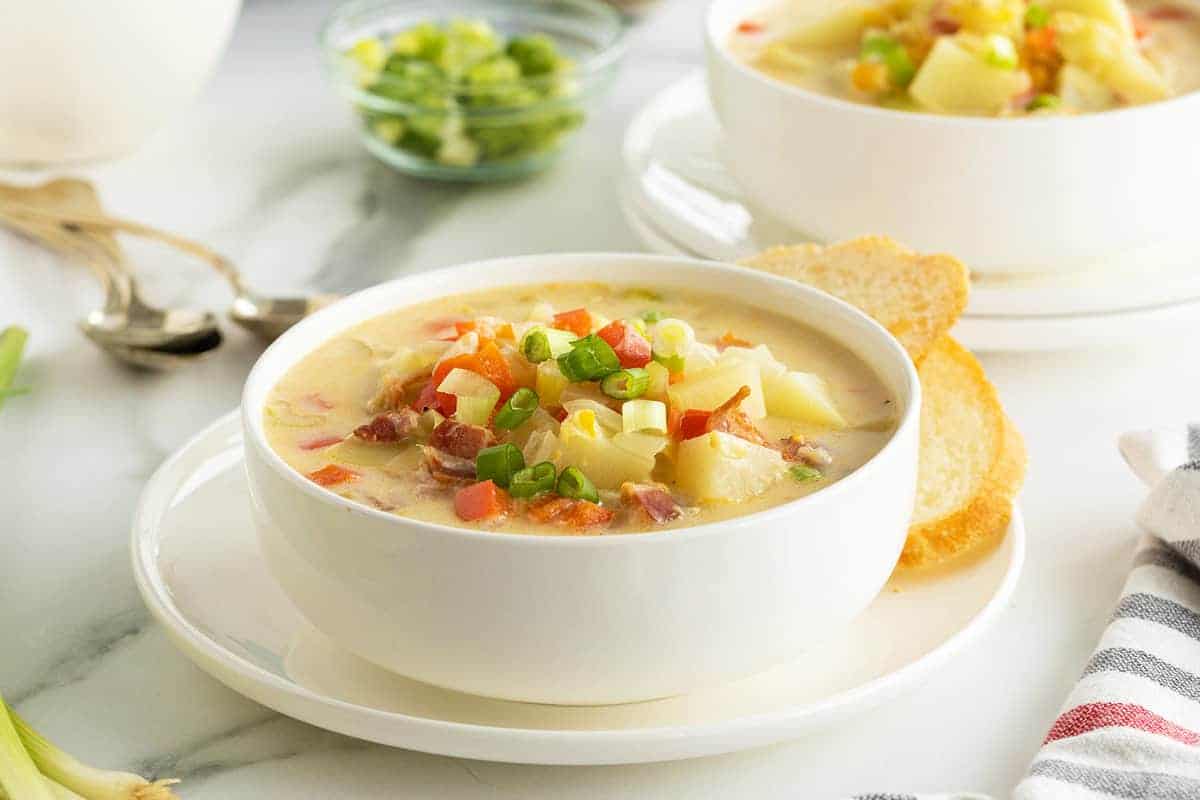 Bowl of creamy corn chowder topped with crispy bacon and fresh herbs.