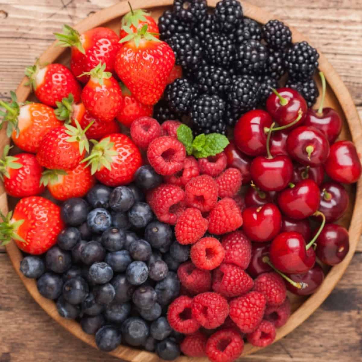 A bowl filled with fresh berries sits on a rustic wooden table.