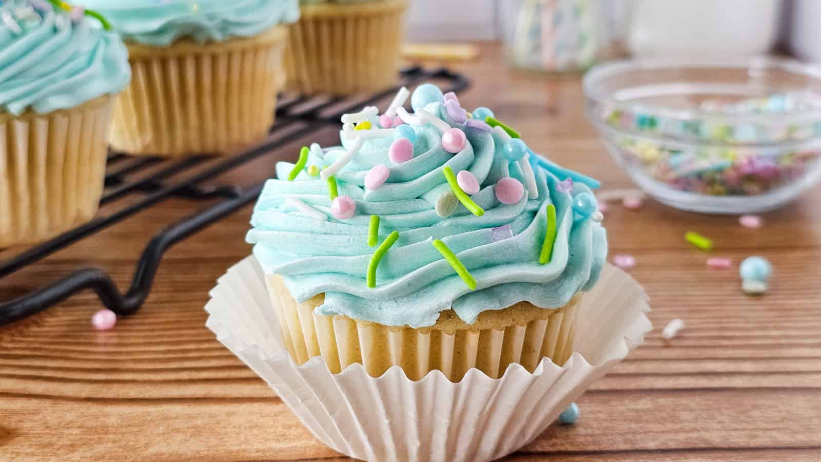 A delicious cupcake with blue frosting rests on a wooden surface.