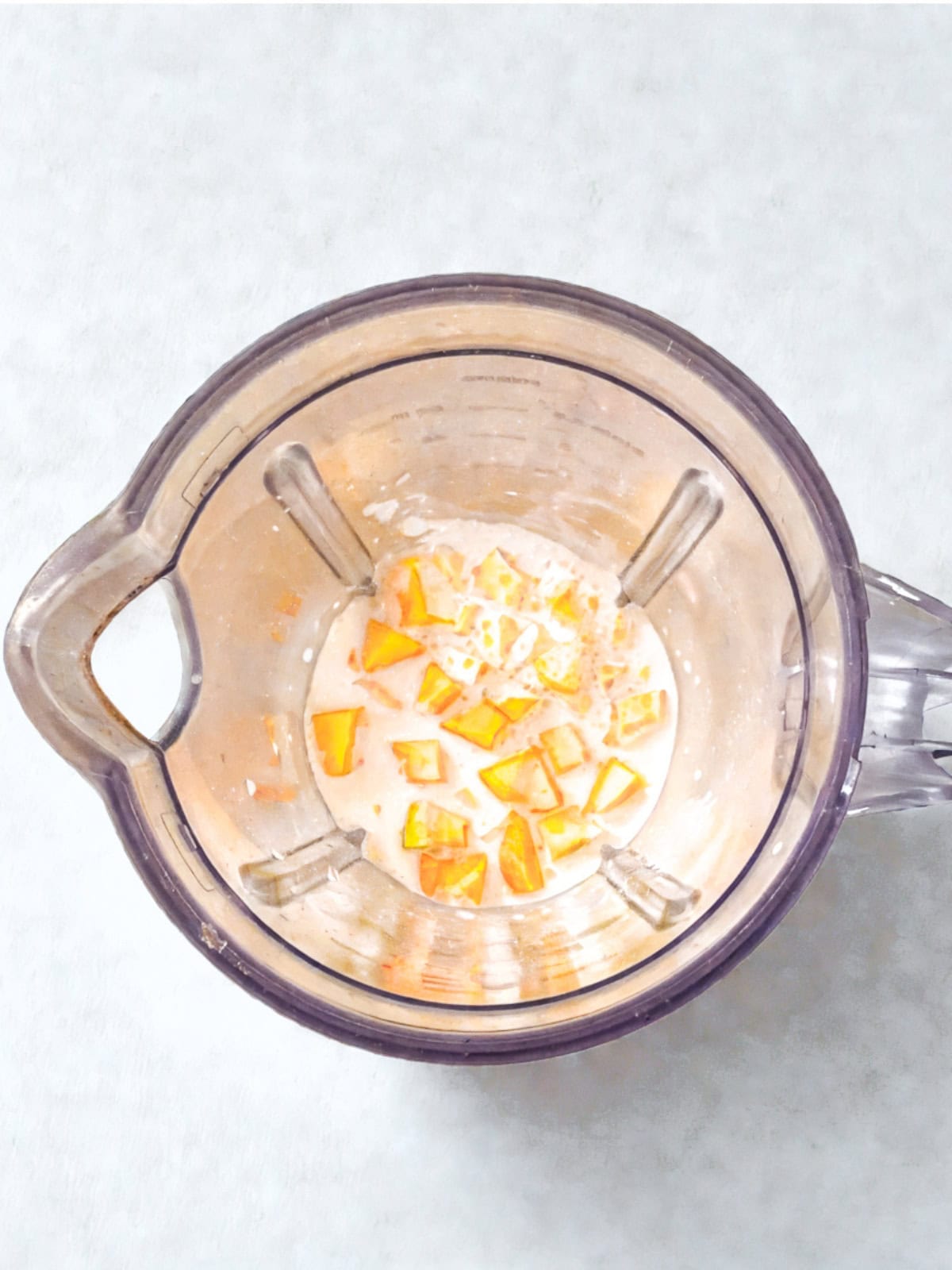 Blender filled with diced mango and mixture, blending ingredients for a mango sago.