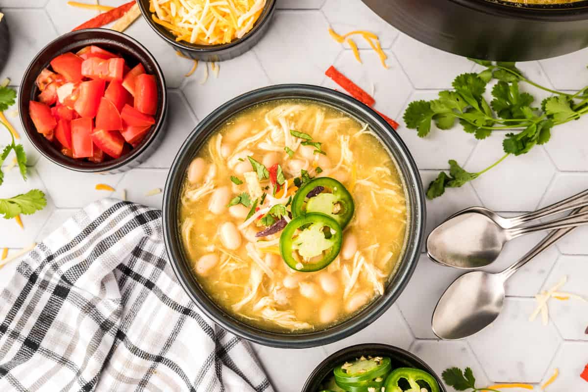 Bowl of white chicken chili with beans and garnish.