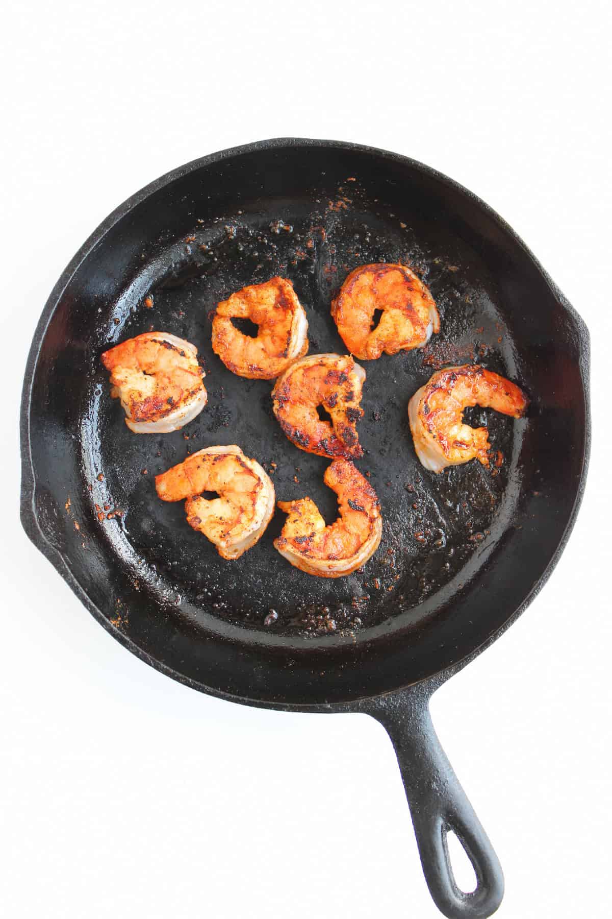 Perfectly blackened shrimp sizzling in a cast iron skillet.
