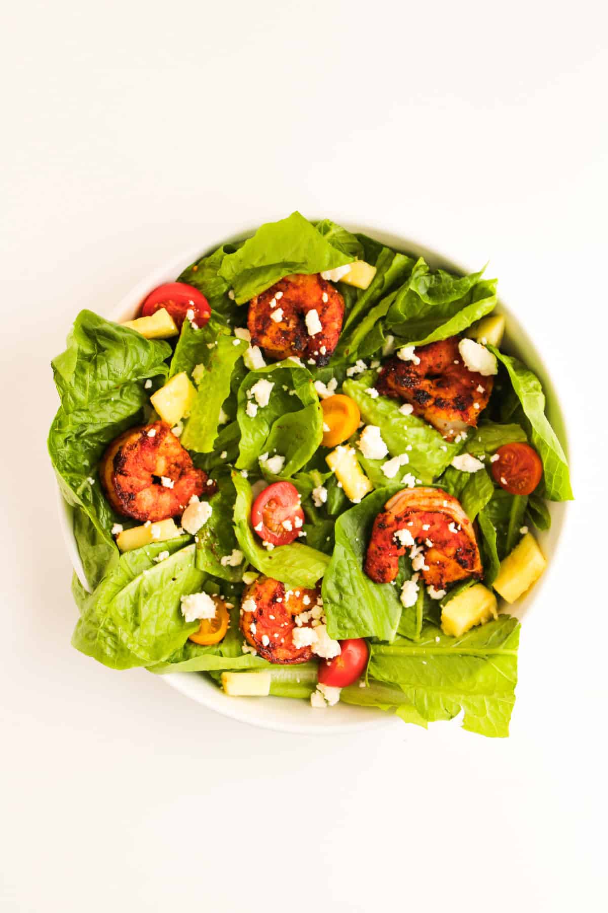 Colorful shrimp salad with romaine, cherry tomatoes, avocado, and crumbled feta cheese.
