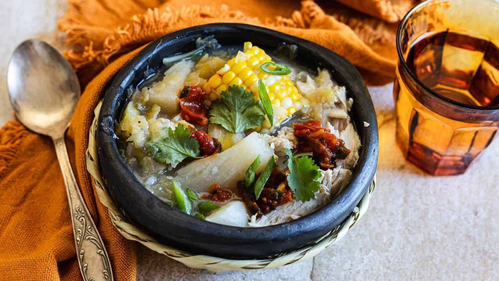 Hearty bowl of chicken sancocho with corn, yucca, and plantains in rich broth.