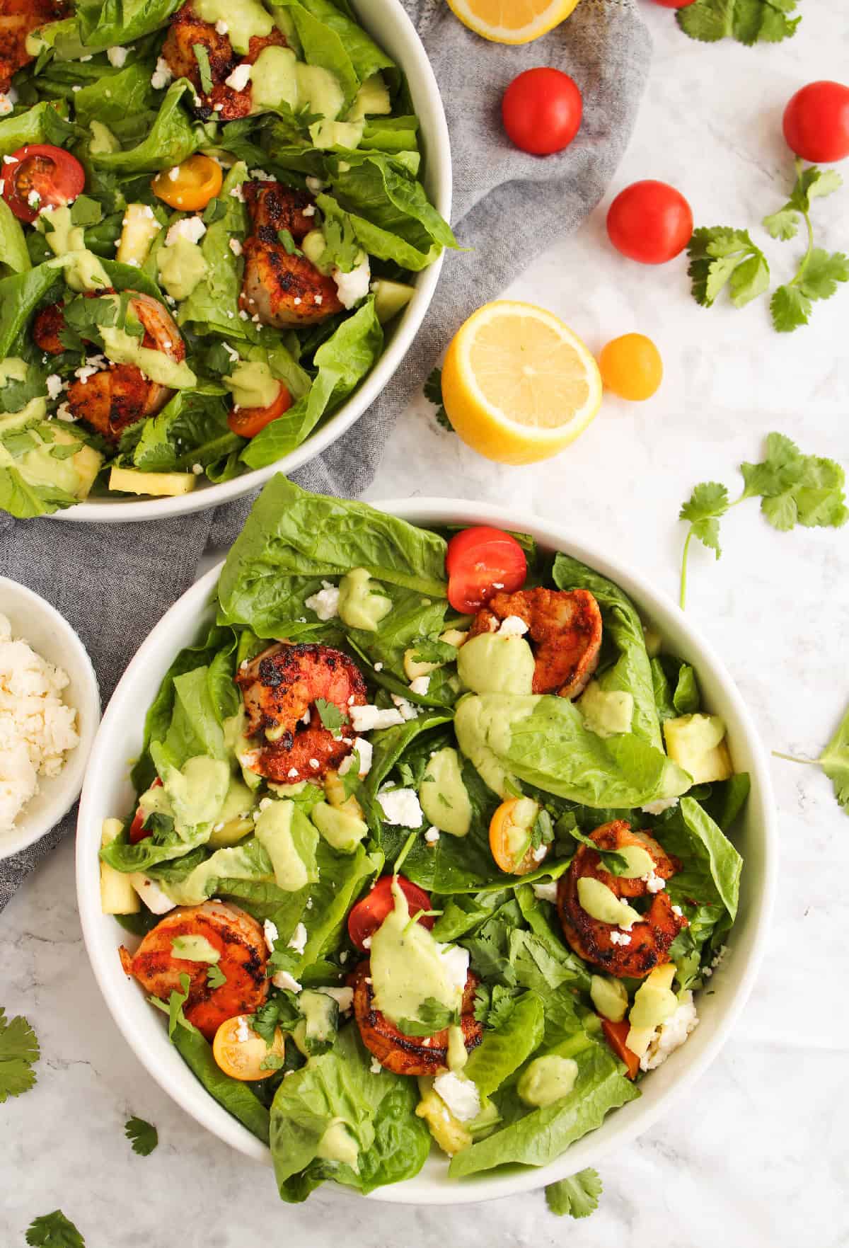 Fresh shrimp salad with grilled blackened shrimp, creamy avocado dressing, cherry tomatoes, and romaine lettuce in a white bowl.