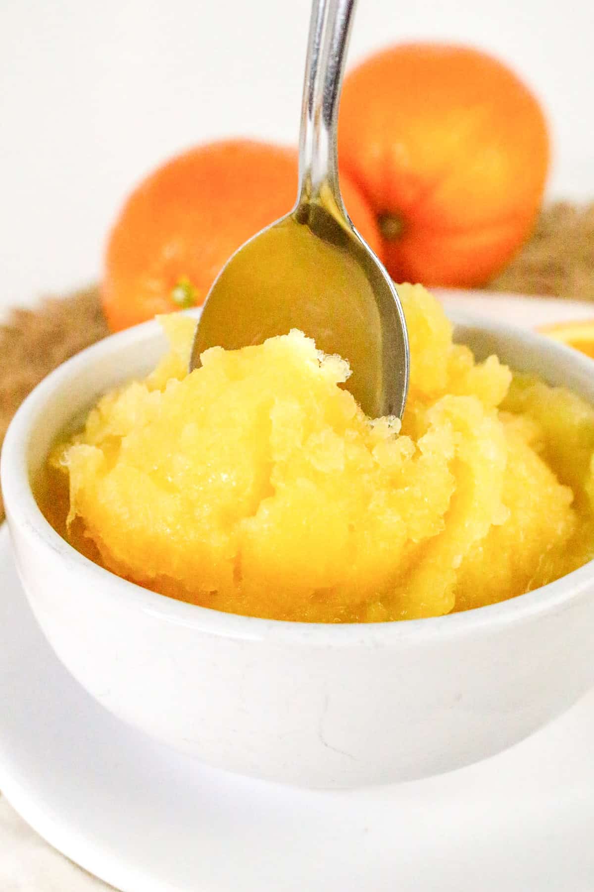 Spoon digging into a bowl of orange sorbet – smooth and refreshing.
