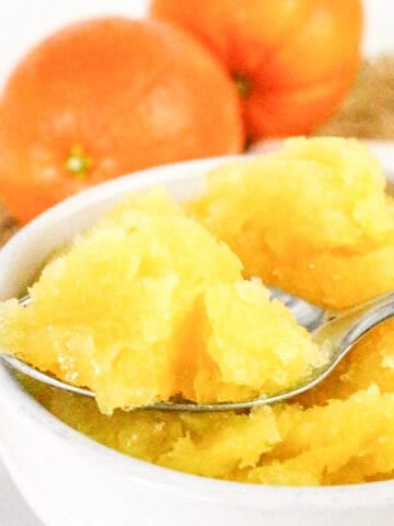Spoonful of fresh orange sorbet lifted from a white bowl.