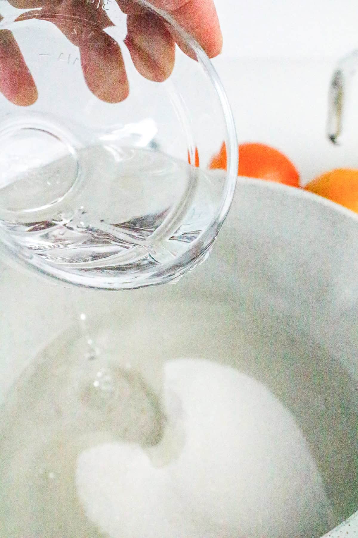 Pouring water into saucepan with sugar for orange sorbet base..