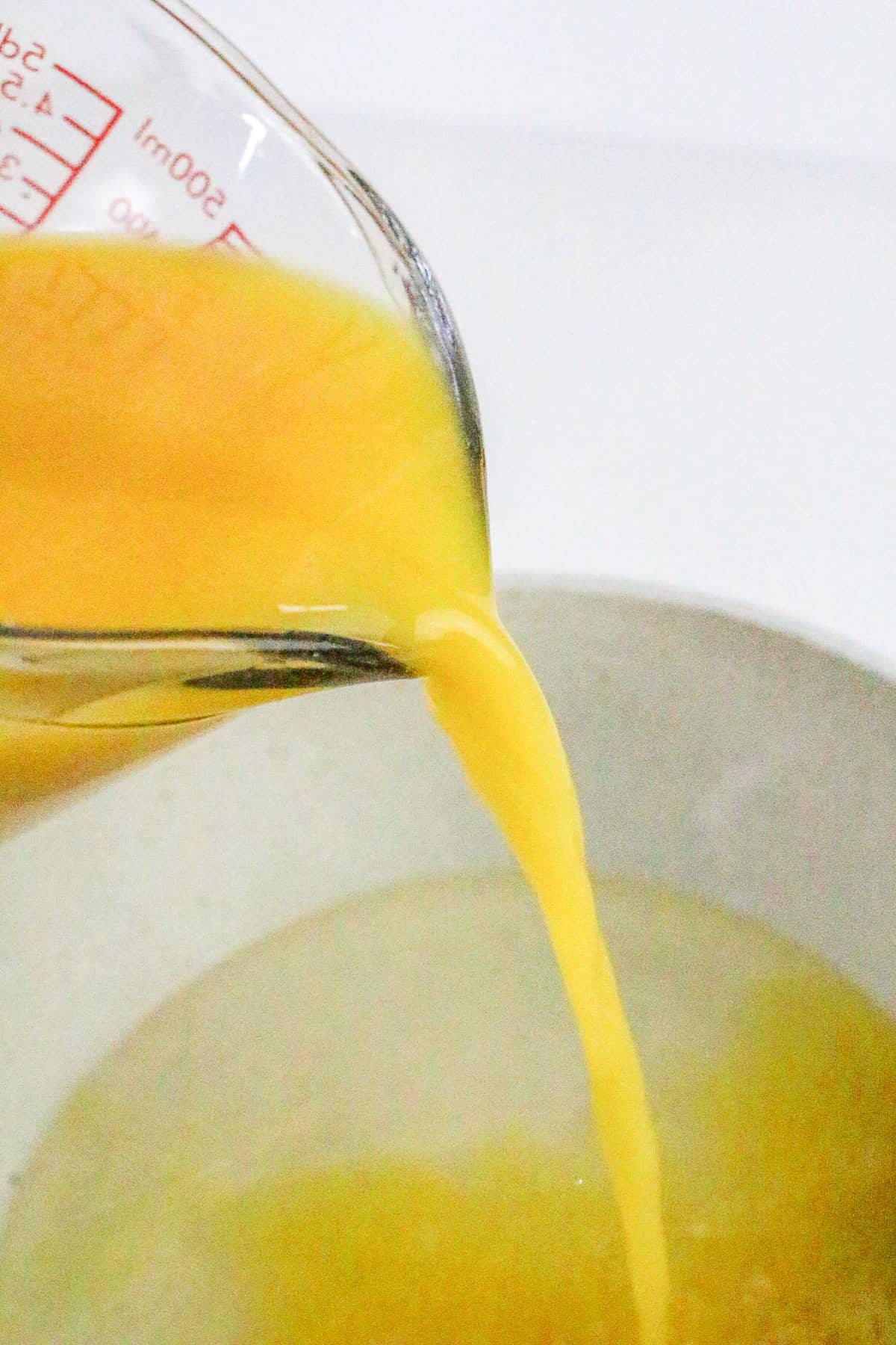 Pouring fresh orange juice into sugar mixture for sorbet.