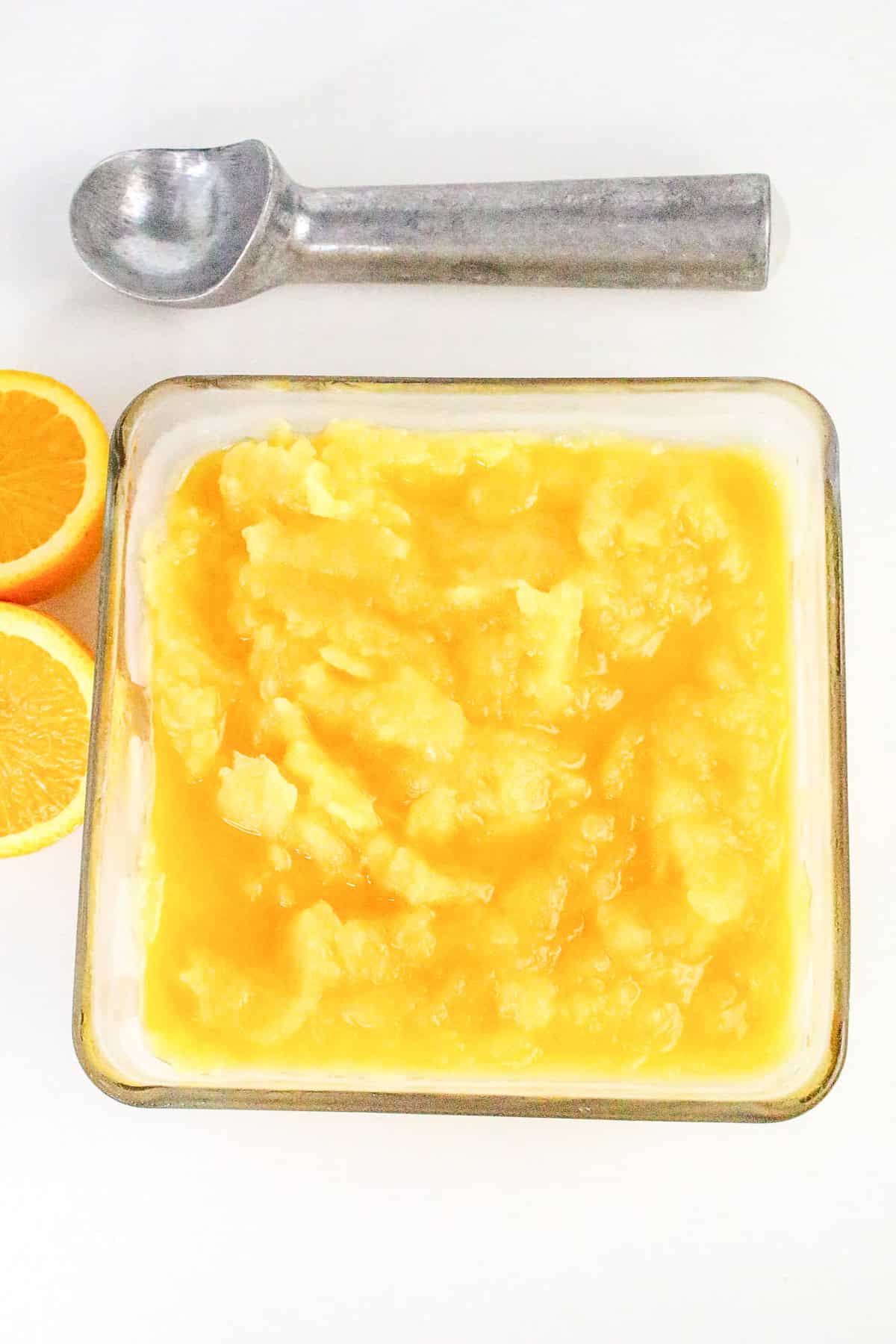 Frozen orange sorbet in dish ready to be scooped.
