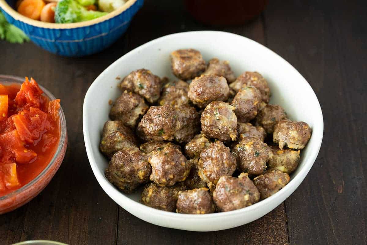 Baked meatballs on a white plate with parsley.