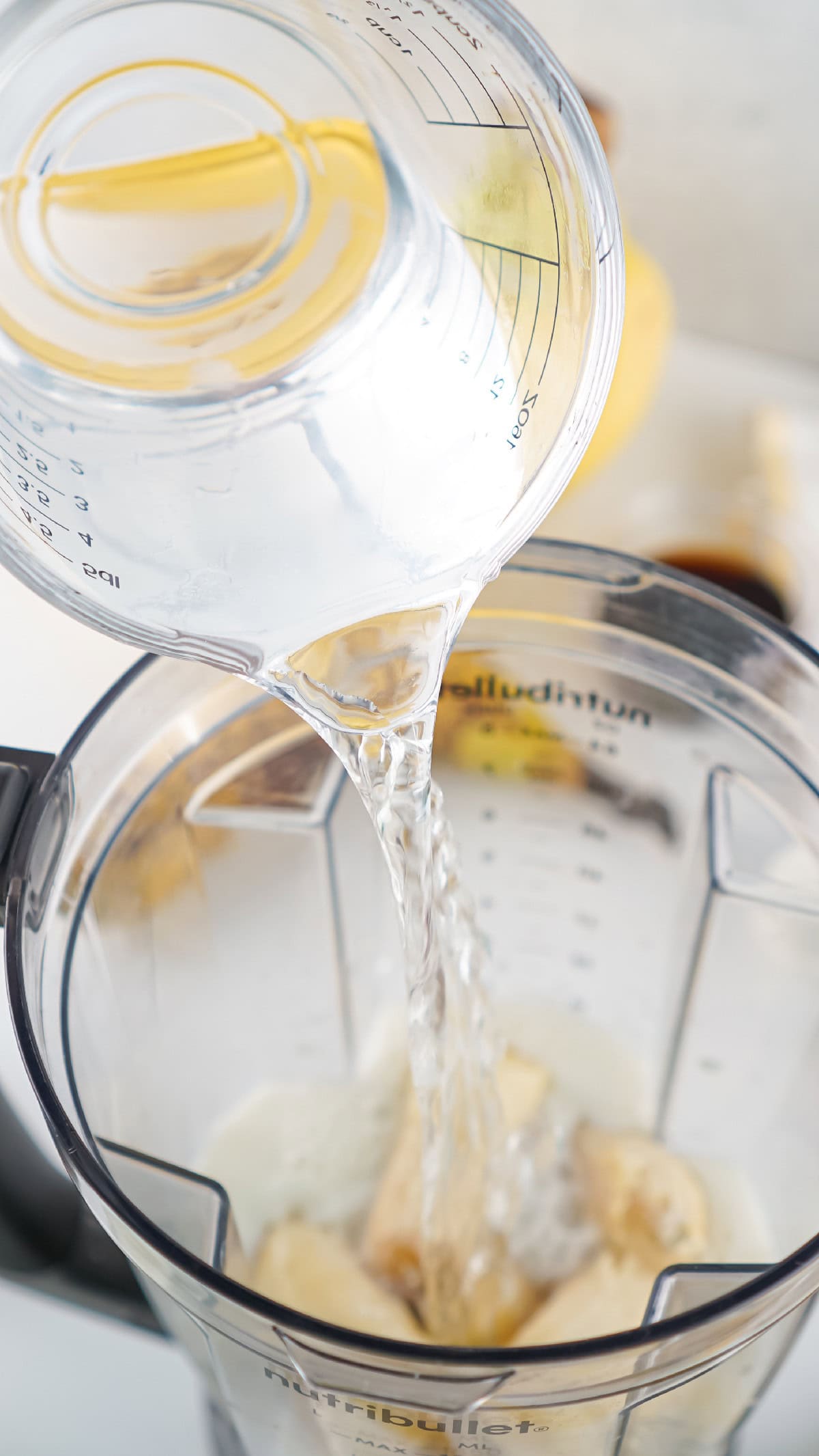 Clear water added to blender with bananas and milk for a creamy banana drink.