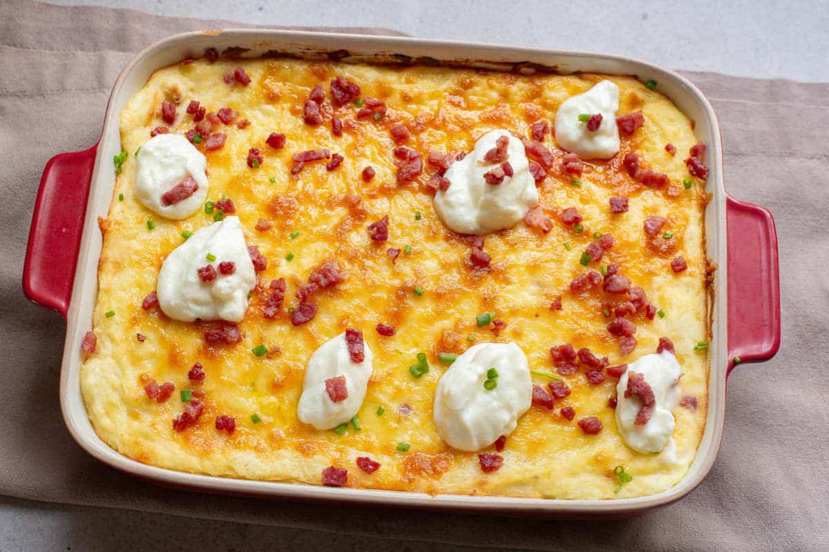 Baked casserole topped with bacon, cheese, and green onions.