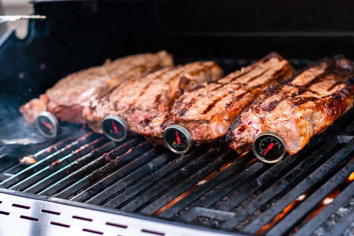 Checking steak temperature on a grill.